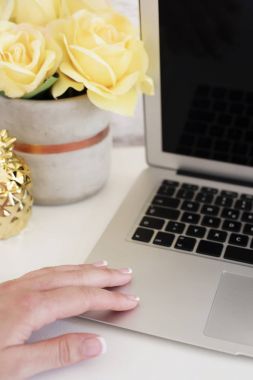 Kadınsı işyeri kavramı. Laptop, çiçek, altın ananas, kadın el ile serbest çalışma alanı. Blogger çalışma. Parlak, sarı ve altın
