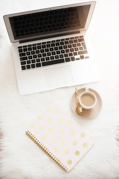 Laptop, Kaffee und Notizbuch auf dem Fußboden auf einem weißen Fellteppich. freiberufliche Mode komfortable Weiblichkeit Home Workspace in flachem Lay-Stil. Draufsicht, rosa und gold. vertikales Bild — Stockfoto