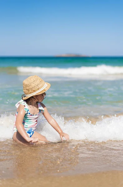 Niña, niña con sombrero de paja y traje de baño floral mirando al mar en un día soleado — Foto de Stock