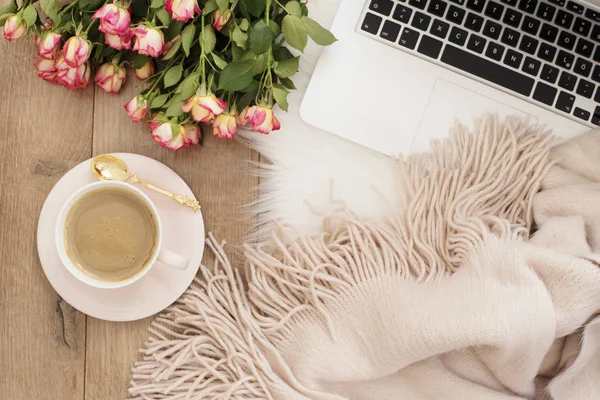 Feminine workplace concept. Freelance workspace with laptop, flowers roses. Blogger working.