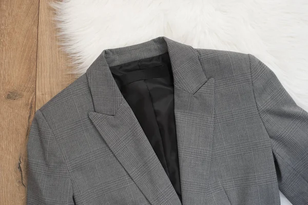 优雅的女式夹克。在木质背景上用灰色夹克方格花纹。时尚与设计概念, 购物 — 图库照片
