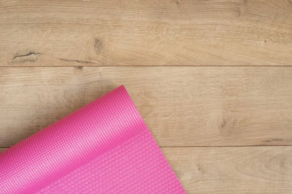 Rosa yogamatta på en träbakgrund. Fitness koncept, aktiv livsstil, kroppsvård koncept. Träbakgrund — Stockfoto