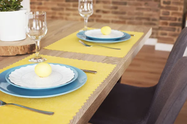 Linda mesa de Páscoa com decorações. Placas azuis em esteiras de alimentação amarelas. Ovos pintados de Páscoa amarela — Fotografia de Stock