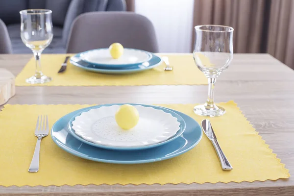 Hermoso ajuste de mesa de Pascua con decoraciones. Placas azules en alfombras de alimentación amarillas. Huevos pintados de Pascua amarillos —  Fotos de Stock