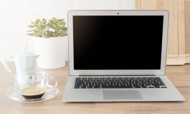 İçişleri Bakanlığı. Evden çalışmak. Boş ekranlı dizüstü bilgisayar. Bir fincan kahve ve mavili İtalyan kahve makinesi. Parlak ve Temiz Minimalist Mutfak, Yakın çekim. Tahta kesme tahtaları, ahşap atölyedeki yeşil sulu tencere..