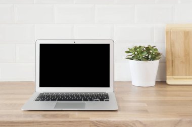 İçişleri Bakanlığı. Evden çalışmak. Modern bilgisayar, boş ekranlı dizüstü bilgisayar. Parlak ve Temiz Modern Minimalist Mutfak, Yakın çekim. Tahta kesme tahtaları, ahşap atölyedeki yeşil sulu tencere..