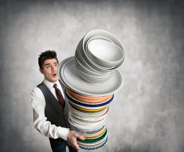 Young waiter holding stack of plates — Stock Photo, Image