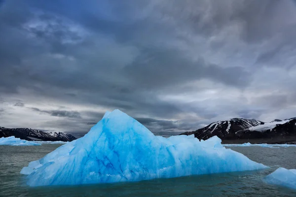 Donkere winter berg met sneeuw, blauwe gletsjerijs met de zee op de voorgrond, Spitsbergen, Noorwegen. — Stockfoto