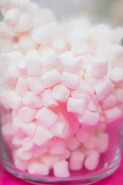 Marshmallows brancos em um jarro de vidro em um fundo rosa — Fotografia de Stock