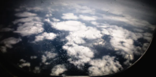 Flores de hielo en la ventana del avión, con montañas y nubes en el fondo — Foto de Stock