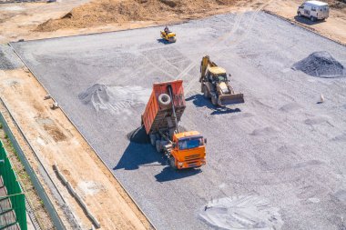 Damperli kamyon asfalt okul stadyumun inşaat sahasında kaldırır