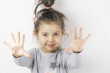 Gülümseyen küçük bir kızın portresi. Elini yüzüne yakın tutan neşeli bir kız. Küçük kız portresi beyaza izole edilmiş.