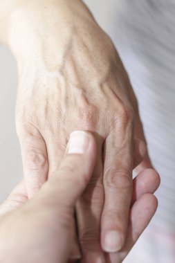 Doktor yaşlı bir kadının elini tutuyor. 