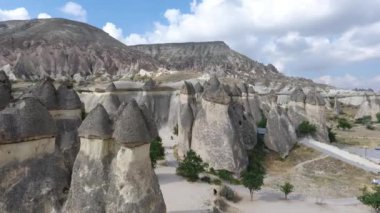 Kapadokya Peri Bacaları Peyzajı. Kapadokya Türkiye 'de taş ev köyü ve kaya oluşumları olan mağara evlerinin 4k Yükselen Hava Aracı görüntüleri 