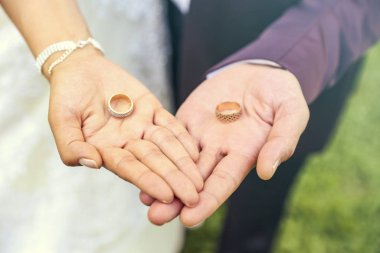 Yeni evlilerin elinde iki alyans. Altın alyanslar. Bir erkek ve bir kadının düğün töreninde değerli metallerden yapılmış alyanslar.. 