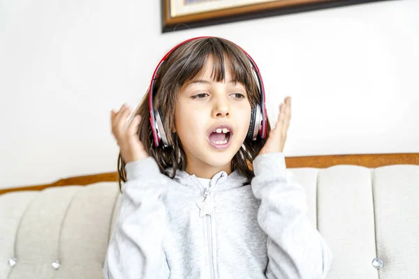 little girl with headphones at home. child girl listening to music.