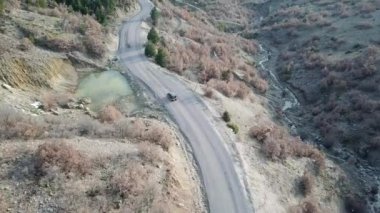 Sonbahar manzarasında dağ ve orman yolunda seyahat eden bir araba. seyahat ve seyahat konsept drone video. 