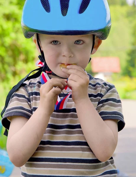 Kleine Siegerin beißt sich an Medaille fest. — Stockfoto