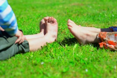 Çocuklar çimlerin üzerinde çıplak ayakla. 