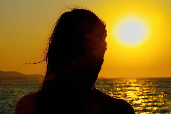 Девушка смотрит закат над морем — стоковое фото