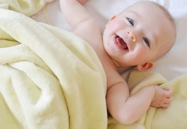 Concepto infantil. Bebé feliz cubierto por una manta amarilla . — Foto de Stock