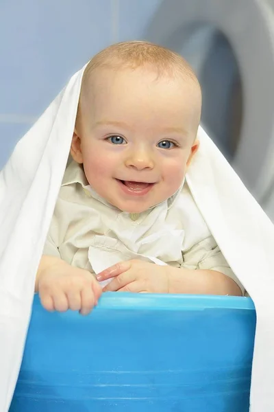 Bebé feliz en la cesta de la ropa delante de la lavadora . — Foto de Stock