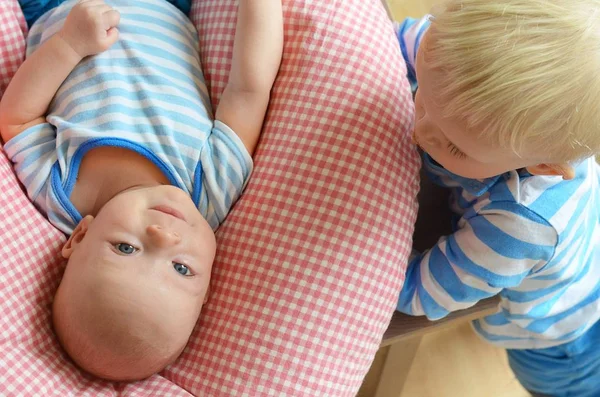 El niño está mirando a su hermano recién nacido acostado en la almohada . — Foto de Stock