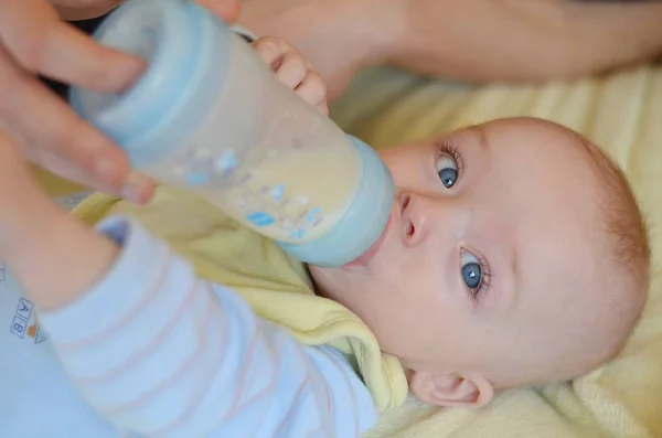 Baby is drinking infant milk from the bottle which parent�s hand holds. — Stock Photo, Image