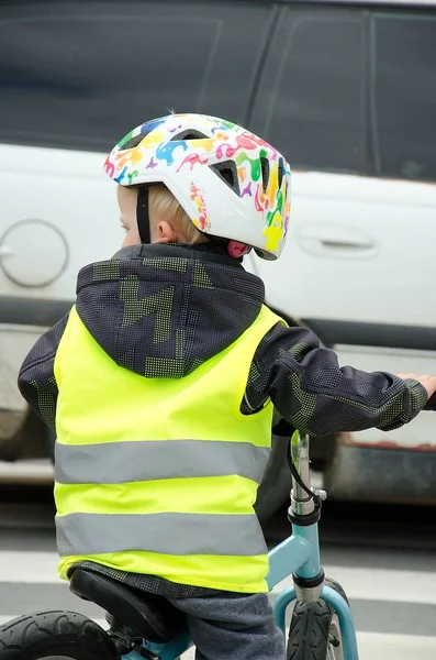 Niebezpieczna sytuacja w ruchu miejskim. Małe dziecko jeździ rowerem po przejściu przez zebrę, podczas gdy biały samochód jedzie przed nim.. — Zdjęcie stockowe