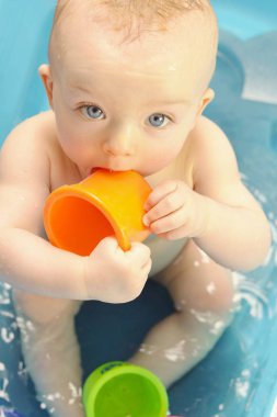 Tüp içinde yıkanırken plastik bardaklarla oynayan tatlı çocuk..