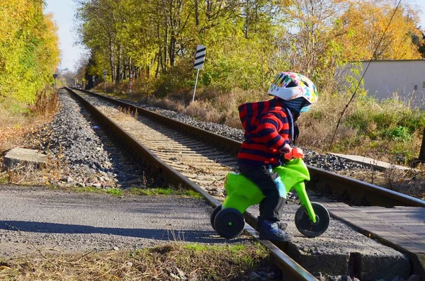 Mały chłopiec jeżdżący na motorze przechodzi przez tory kolejowe.. — Zdjęcie stockowe