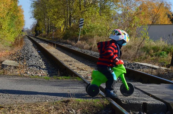 Mały chłopiec jeżdżący na motorze przechodzi przez tory kolejowe.. — Zdjęcie stockowe