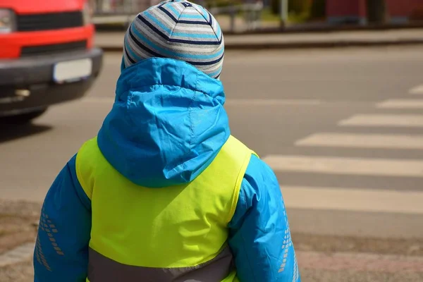 Mały chłopiec przekroczy granicę zebry, gdzie zbliża się czerwony samochód.. — Zdjęcie stockowe