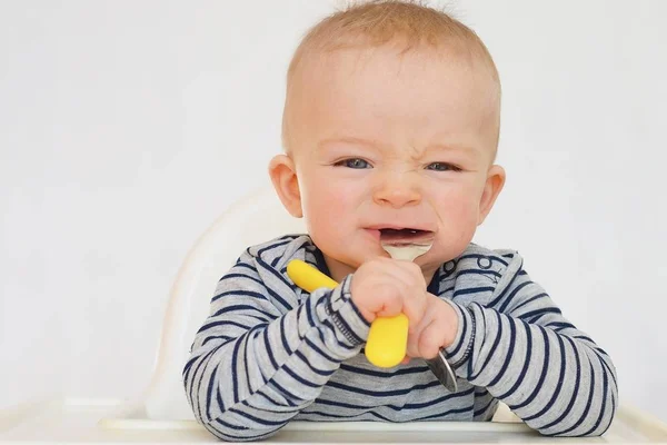 Portrait of baby learning to eat with fork and spoon 로열티 프리 스톡 사진