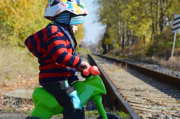 Küçük çocuk, tren yolunun önünde motosikletini sürüyor.. — Stok fotoğraf