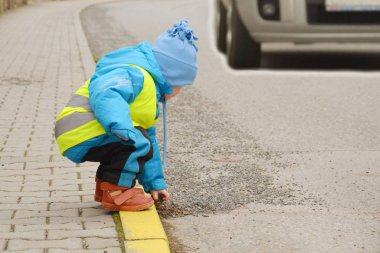 Küçük bir çocuk yol kenarında taşlarla oynuyor.. 
