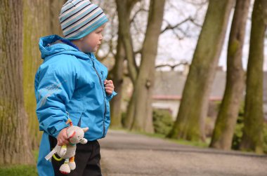 Küçük çocuk tılsımıyla parkta mutlu bir şekilde yürüyor..