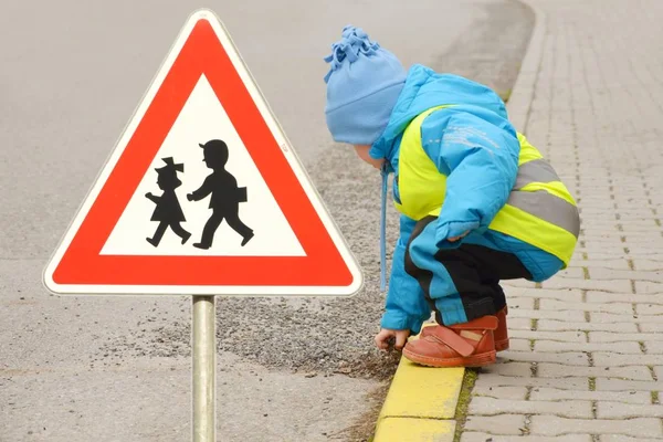 Bambino piccolo che gioca con pietre su un ciglio della strada da solo . — Foto Stock