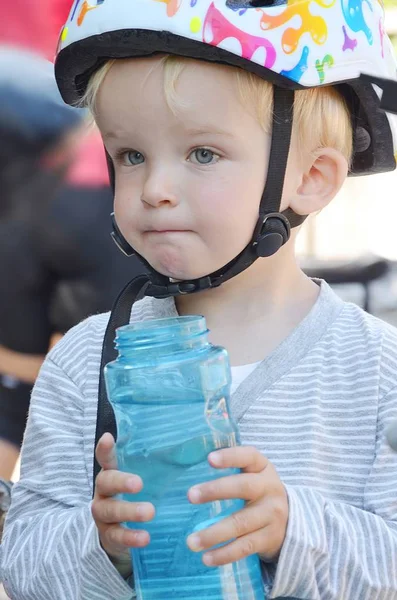 Kleiner Junge mit einer blauen Flasche Wasser. — Stockfoto