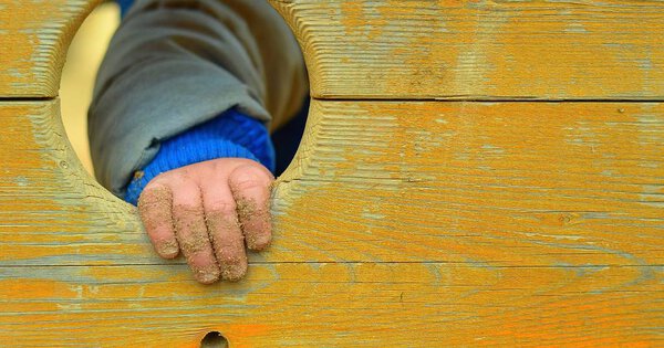 Hand of small boy in the old wooden hole. Child concept.