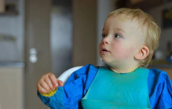 Mały chłopiec ubrany na niebiesko i siedzący na krześle wybiera co jeść. Koncepcja dziecka. — Zdjęcie stockowe