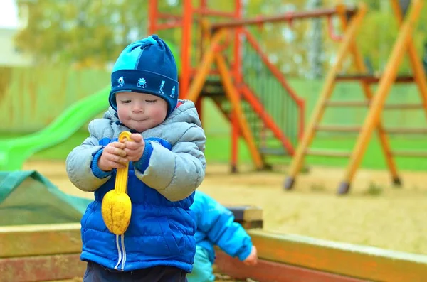 Mały chłopiec bawiący się samotnie na placu zabaw. — Zdjęcie stockowe