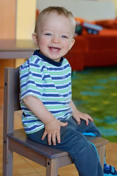 Szczęśliwy chłopiec siedzi na swoim pierwszym drewnianym krześle. Koncepcja dziecka. — Zdjęcie stockowe