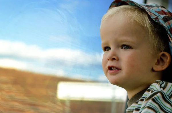 Mały blond chłopiec patrząc z okna pociągu na ladscape. — Zdjęcie stockowe