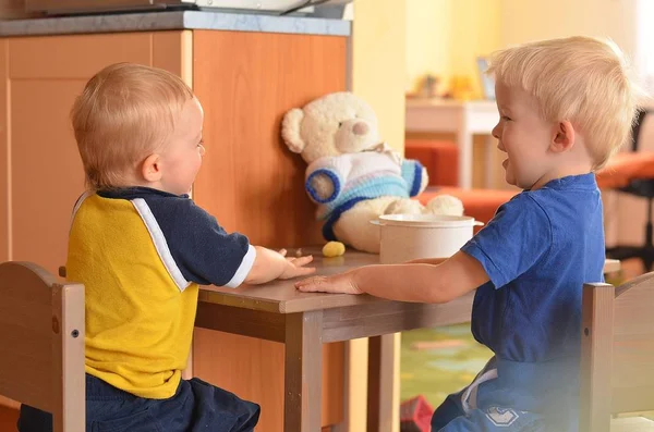 Dos hermanitos sentados juntos en la mesa son felices . — Foto de Stock