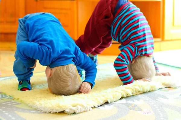 Los niños están entrenando a pie de manos en la cabeza. Lindos niños haciendo ejercicio en casa desde temprana edad . — Foto de Stock