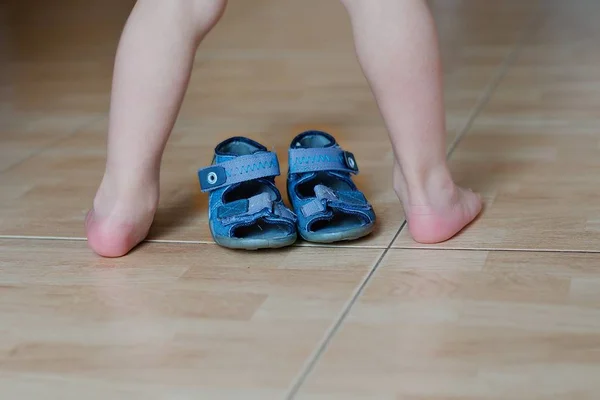 Контраст босых детских ног и обуви — стоковое фото