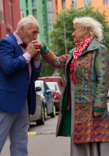Старик целует руки старухе на улице — стоковое фото