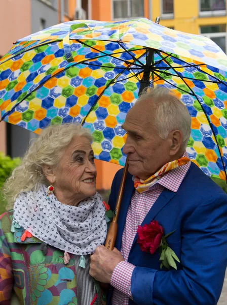 Zarif yaşlı çift bir umbre altında açık havada yürüyüş giyinmiş — Stok fotoğraf