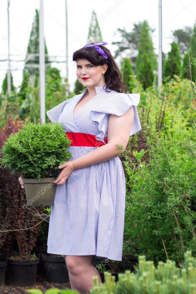 Young beautiful plus size Girl keeps pot with  plant.